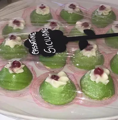 a plastic tray of green cupcakes with white and black icing at Hotel Baia Di Venere in San Vito lo Capo