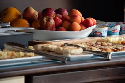 a buffet with a bowl of apples and oranges at Hotel Baia Di Venere in San Vito lo Capo