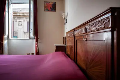 a bedroom with a wooden bed and a window at B&B Novecento in Palermo