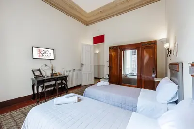 a hotel room with two beds and a desk at B&B Novecento in Palermo