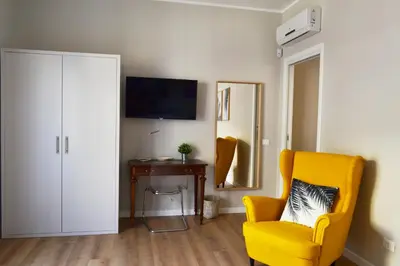 a living room with a yellow chair and a television at REALE ORLEANS in Palermo