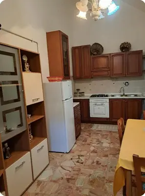 a kitchen with a white refrigerator and wooden cabinets at Casa Mimì in Castellammare del Golfo
