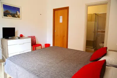 a bedroom with a bed with red pillows and a television at B&B Siciliò in Santa Flavia