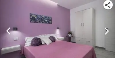 a pink bedroom with a bed with purple walls at Appartamento solare in Castellammare del Golfo