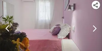 a bedroom with a pink bed and a clock on the wall at Appartamento solare in Castellammare del Golfo