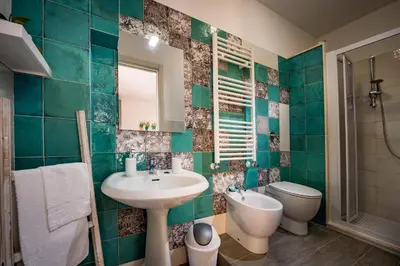a green tiled bathroom with a sink and a toilet at Piccolo Sole d'oro - appartamenti in Calatafimi