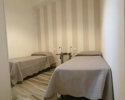 two beds in a room with striped walls at Casa Margò in Monreale