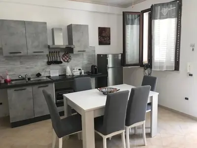 a kitchen with a table and chairs in a kitchen at Appartamento 60 mq a 800 mt dalla spiaggia in Capaci