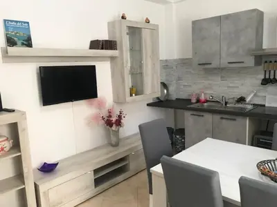 a kitchen with a table and a tv on the wall at Appartamento 60 mq a 800 mt dalla spiaggia in Capaci