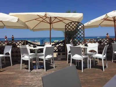 a row of tables and chairs with umbrellas on a beach at Appartamento 60 mq a 800 mt dalla spiaggia in Capaci