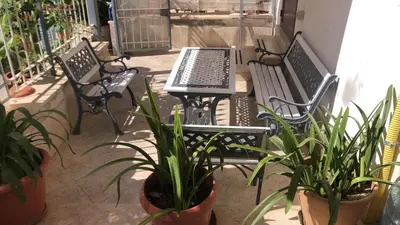 two benches and a table and potted plants on a balcony at Appartamento 60 mq a 800 mt dalla spiaggia in Capaci