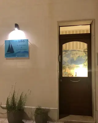 a black door with a sign on the side of a building at B&b IL FIOCCO E LA RANDA in San Vito lo Capo