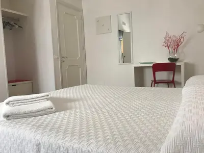 a bedroom with a white bed with two towels on it at B&b IL FIOCCO E LA RANDA in San Vito lo Capo
