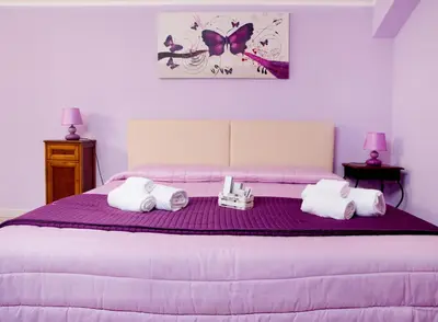 a bedroom with a purple bed with towels on it at Sosta dei Garibaldini in Campofelice di Roccella