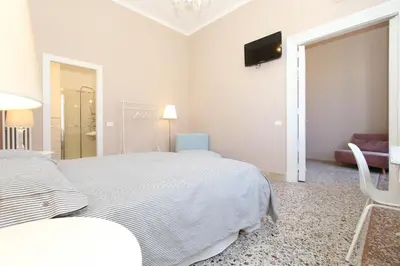 a white bedroom with a bed and a tv on the wall at Le case d'un tempo in Palermo