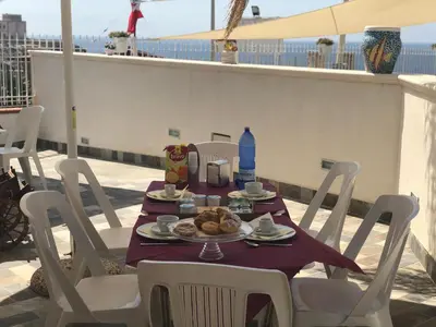 a table with a plate of food on a balcony at La Ruota B&B in Terrasini