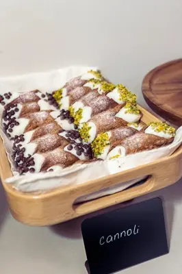 a cake on a wooden tray with a sign that says cannolis at Casa Nostra Boutique Hotel & Spa in Palermo