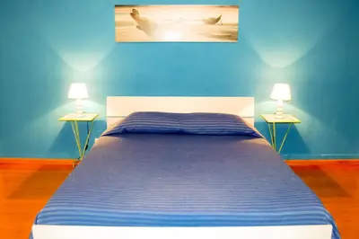 a blue bedroom with a bed with two lamps at Cheap in Center in Palermo