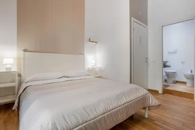 a white bedroom with a large bed and a bathroom at B&B Palermo Bella Rooms and Suites in Palermo