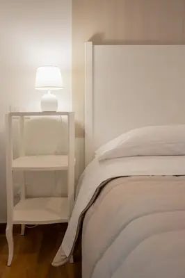 a white bed with a white lamp on a night stand at B&B Palermo Bella Rooms and Suites in Palermo