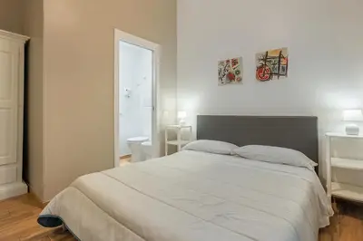a bedroom with a white bed and a bathroom at B&B Palermo Bella Rooms and Suites in Palermo