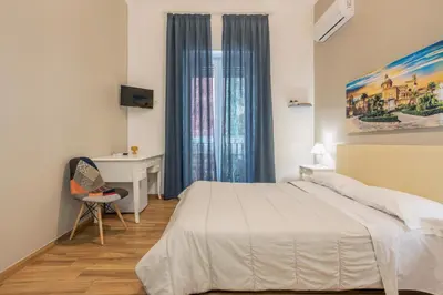 a bedroom with a bed and a desk and a window at B&B Palermo Bella Rooms and Suites in Palermo