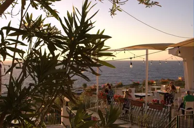 a group of people sitting at tables near the ocean at Bellevue del Golfo Hotel & Spa in Sferracavallo