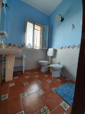 a blue bathroom with a toilet and a sink at L'Opuntia sul lago in Caccamo