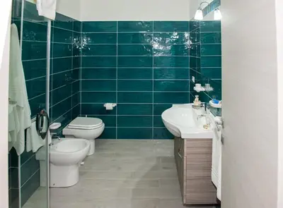 a green tiled bathroom with a toilet and a sink at Da Ida e Gianni in Castellammare del Golfo