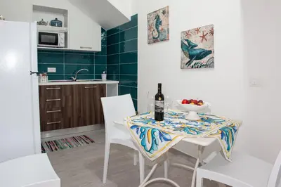 a dining room table with a bottle of wine and a bowl of fruit at Da Ida e Gianni in Castellammare del Golfo