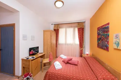 a bedroom with a bed with red sheets and pink pillows at Hotel Halimeda in San Vito lo Capo