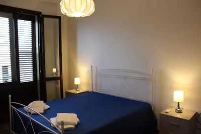 a bedroom with a bed with blue sheets and two lamps at Palazzo del Golfo in Castellammare del Golfo