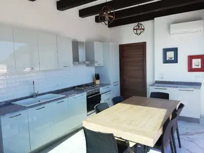 a kitchen with a wooden table and a kitchen with blue cabinets at Palazzo del Golfo Penthouse in Castellammare del Golfo