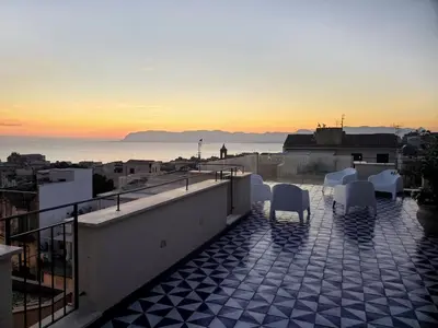 a balcony with a view of the ocean at sunset at Palazzo del Golfo Penthouse in Castellammare del Golfo