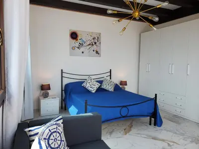 a bedroom with a blue bed and a couch at Palazzo del Golfo Penthouse in Castellammare del Golfo