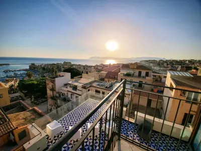 a view of a city from a balcony with the sunset at Palazzo del Golfo Penthouse in Castellammare del Golfo