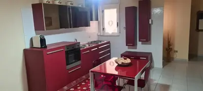 a kitchen with red cabinets and a table in it at Giusy's Place 2.0 in Campofelice di Roccella