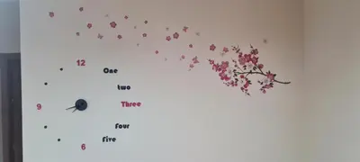 a clock with pink flowers on a white wall at Giusy's Place 2.0 in Campofelice di Roccella