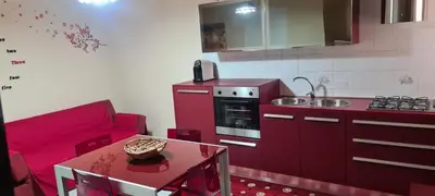 a red kitchen with a red couch and a table at Giusy's Place 2.0 in Campofelice di Roccella