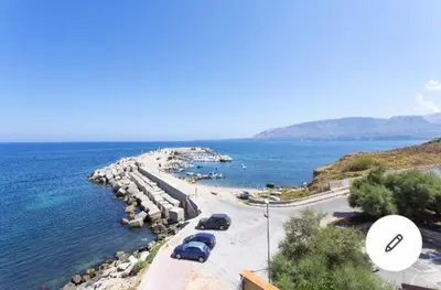 a group of cars parked on a road next to the water at la casa al mare in Trappeto