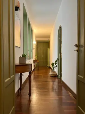 a hallway with a wooden floor and green doors at Baru's House in Palermo