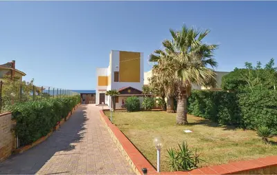 a house with a palm tree and a sidewalk at Villa Mucera in Ficarazzi