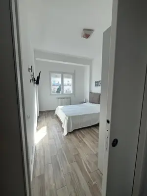 a white bedroom with a bed and a wooden floor at Calalula Apartment Palermo in Palermo