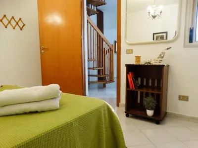 a bedroom with a bed with a green blanket and a staircase at Holiday Home Sferracavallo in Palermo