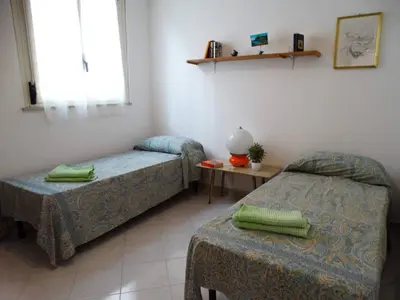 a room with two beds and a table and a window at Holiday Home Sferracavallo in Palermo