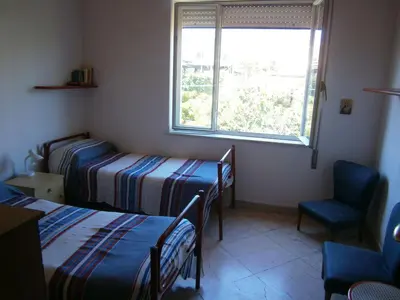 a room with two beds and a window and a chair at Terrazza sul mare in Trabia
