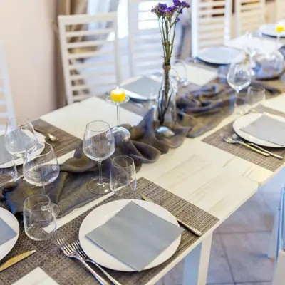 a dining table with white plates and glasses and purple flowers at Hotel Centrale Bagheria in Bagheria