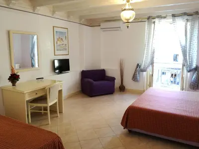a bedroom with two beds and a desk and a purple chair at Hotel Centrale Bagheria in Bagheria