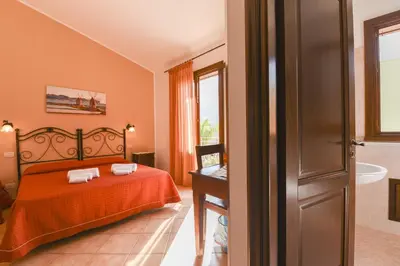a bedroom with a bed with orange sheets and a tub at Aurora Castelluzzo in Castelluzzo
