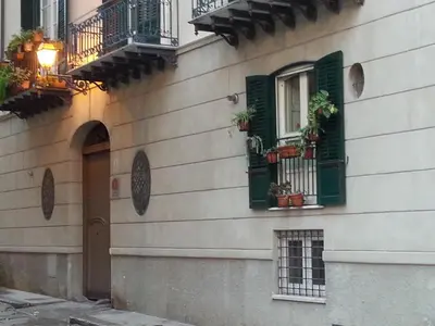 a building with green shuttered windows and potted plants at Abatellis Luxury in Palermo